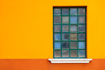Window on the orange wall of the house. Colorful architecture in Burano island, Venice, Italy.