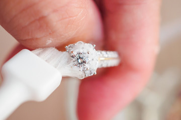 Jeweller hand cleaning and polishing vintage jewelry diamond ring closeup macro