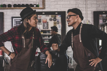 portrait of two stylist barber hairdresser with apron standing at barbershop.