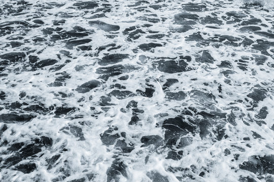 Dark water of stormy sea and white foam. Horizontal color photography.