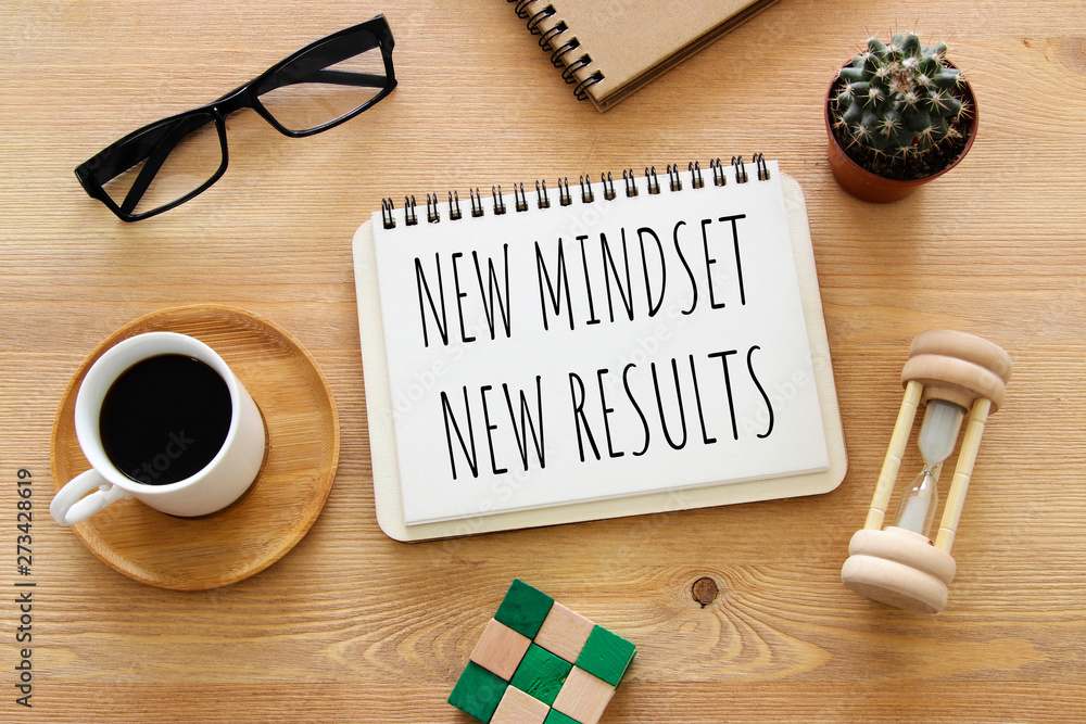 Poster top view image of table with open notebook and the text new mindset new results. success and persona