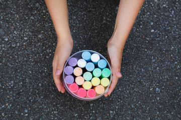 Set of new colorful chalks isolated on grey pavement of sidewalk background. Child ready to make drawings outdoors. Horizontal color photography.
