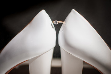 Golden ring with diamond between a pair of white shoes