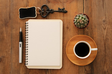 Open notebook with empty pages and other office supplies over wooden old office desk table. Top view, flat lay