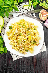 Fusilli with chicken and zucchini in plate on dark board top