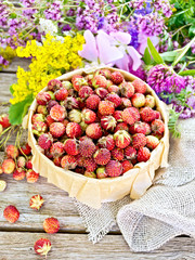 Strawberries in box with flowers on wooden board