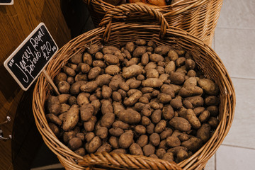 New potatoes in a rattan bucket in shop with price sign.