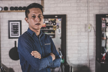 Handsome Asian man crossed his arm in front of barbershop chair