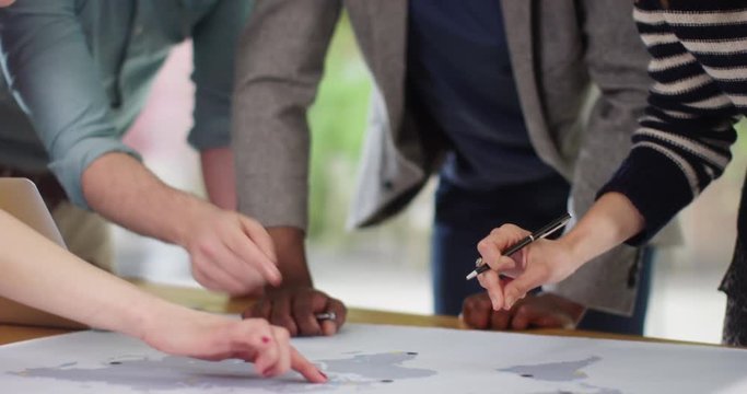 4K Close up hands & faces of multiracial international business team with world map. Slow motion.