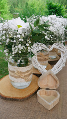 White daisy bouquets in glass jars, open wooden heart box and wattle white heart in the garden