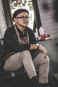 portrait of stylist barber sitting at barbershop chair