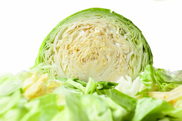 Cabbage head cut in half, isolated on a white background, with shredded cabbage leaves in foreground