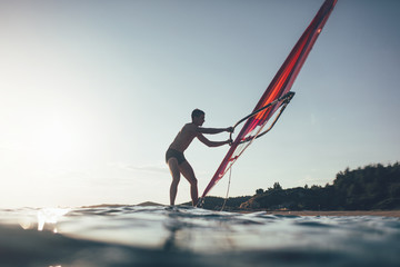 Silhouette of surfer balancing on windsurf board