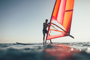 Fototapeta na wymiar Young windsurfer catch the wind on windsurf board