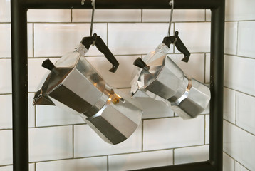Pair of Moka Coffee Pots Hanging on the White Tiled Wall