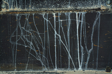 Old dark metal surface with drips of white paint