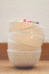 white bowls stacked with colorful cereals inside the bowl above