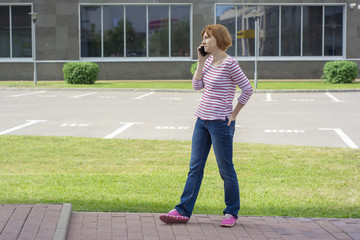 Red-haired middle-aged woman with freckles talking on a mobile phone.