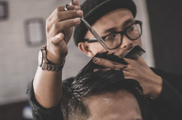 Portrait of barber making hair cut of his attractive man in barbershop