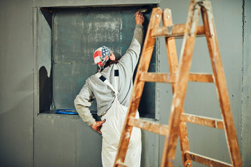 Painter painting walls with a paintbrush indoors.
