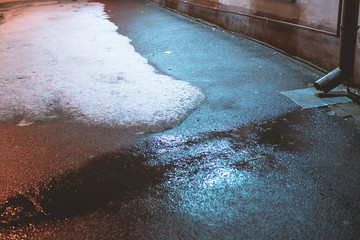 melting snow on the pavement at night in the city. beautiful night reflections on wet pavement in...