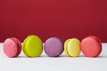 Five multicoloured macaroons on a red and white background. Close-up