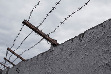 Concrete fence with barbed wire. Freedom, jail, prison, human rights, refugees concept.