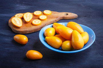 kumquats in a blue plate on a black wooden background