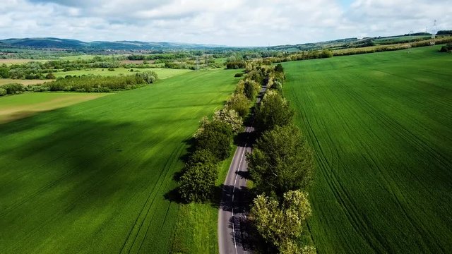 Aerial landscape shot of cloudy bright and shady view of agricultural areas hills following road vehicles passing by summer zala county hungary europe