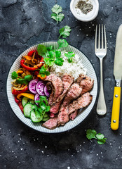 Balanced power buddha bowl - grilled beef steak, roasted and fresh vegetables, rice on a dark background, top view. Healthy diet food concept