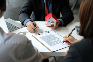 couple buying renting house signing mortgage contract agreement with realtor real estate agent. - obrazy, fototapety, plakaty