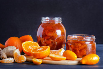 Tangerine and kumquat jam in a glass jar on a black wooden  background.