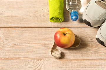 Gray running shoes and fitness accessories on wooden background. Empty text space.