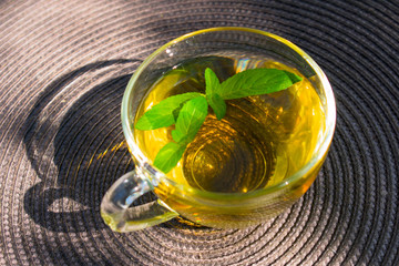  A cup of mint tea with mint leaves on the table. © Olivka888