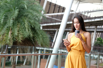 woman holding coffee cup & smart phone outdoor