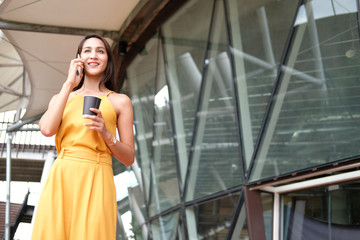 woman holding coffee cup & talking on smart phone outdoor