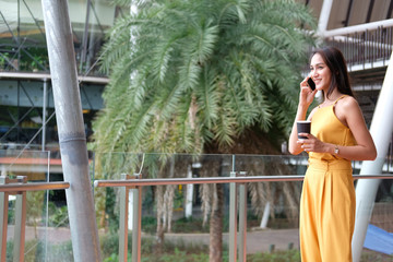 woman holding coffee cup & talking on smart phone outdoor