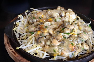 Close up soft oyster omelette with bean sprouts in black hot pan with chilli sauce look delicious.