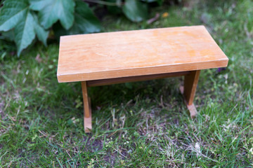 Small angular wooden table on green grass in the garden