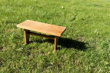 Small angular wooden table on green grass in the garden