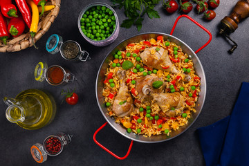 Arroz con pollo. Baked pieces of chicken with bone, rice with paprika and peas.