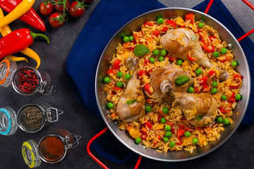 Arroz con pollo. Baked pieces of chicken with bone, rice with paprika and peas.