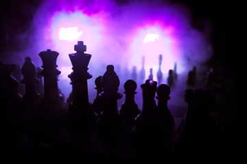 Fototapeta premium Chess board game concept of business ideas and competition. Chess figures on a dark background with smoke and fog.
