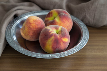 the peach in the copper plate on the wooden background for concept. 