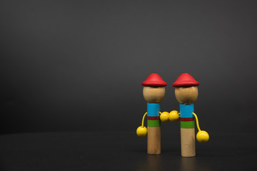 2 colored puppets holding hands standing on the right side of black background