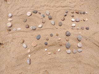 Fototapeta na wymiar Love you writen at sand and created from colorful stones. 