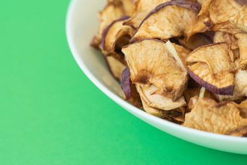 dried apples in white plate on green background