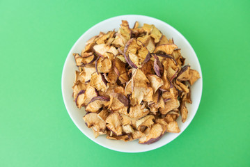 dried apples in white plate on green background