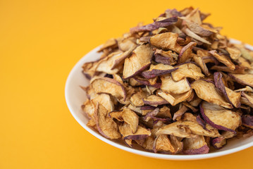 dried apples in white plate on yellow background