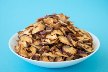 dried apples in white plate on blue background